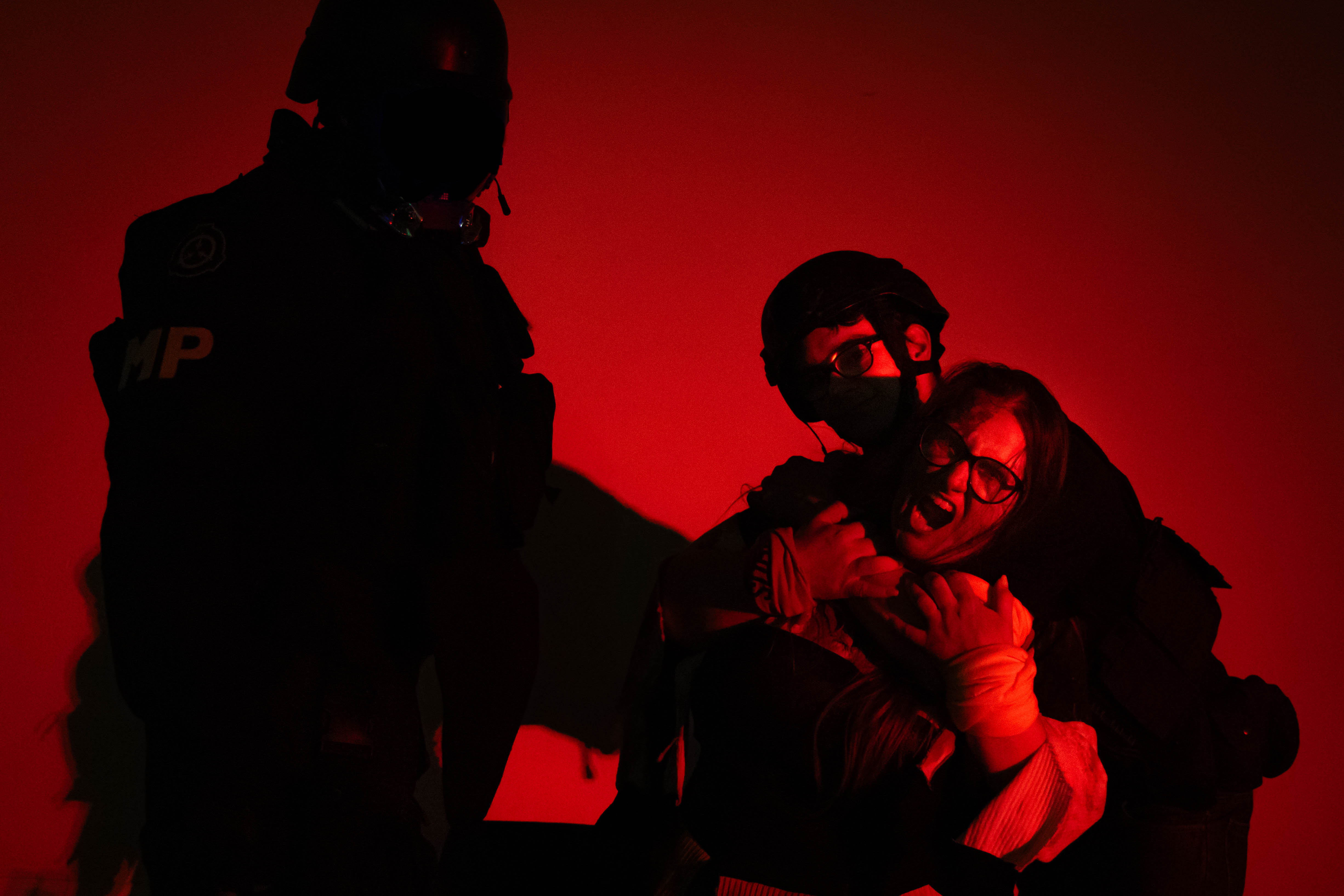A survivor pressed against a wall in the dark, listening